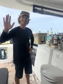 A friendly crew member greets guests aboard the boat, showcasing the interior space with a well-stocked bar area — perfect for entertaining on the water.