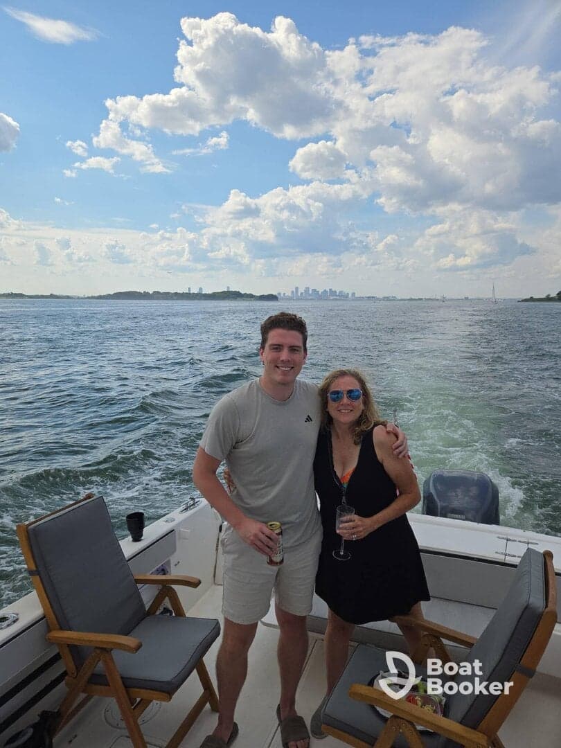 A cheerful couple enjoys drinks on a boat with a stunning city skyline in the background, perfect for memorable outings and celebrations on the water.
