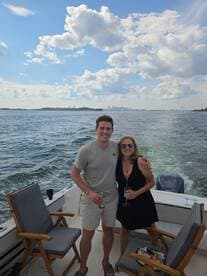 A cheerful couple enjoys drinks on a boat with a stunning city skyline in the background, perfect for memorable outings and celebrations on the water.