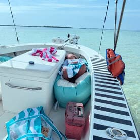 A child relaxes on a comfortable bean bag inside a boat, surrounded by beach towels and a serene water view — perfect for family outings and relaxation on the water.