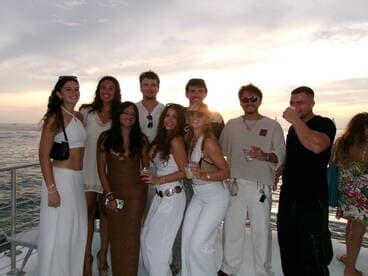 A lively group of friends celebrates at sunset aboard a boat, enjoying drinks and each other's company — perfect for memorable gatherings on the water.
