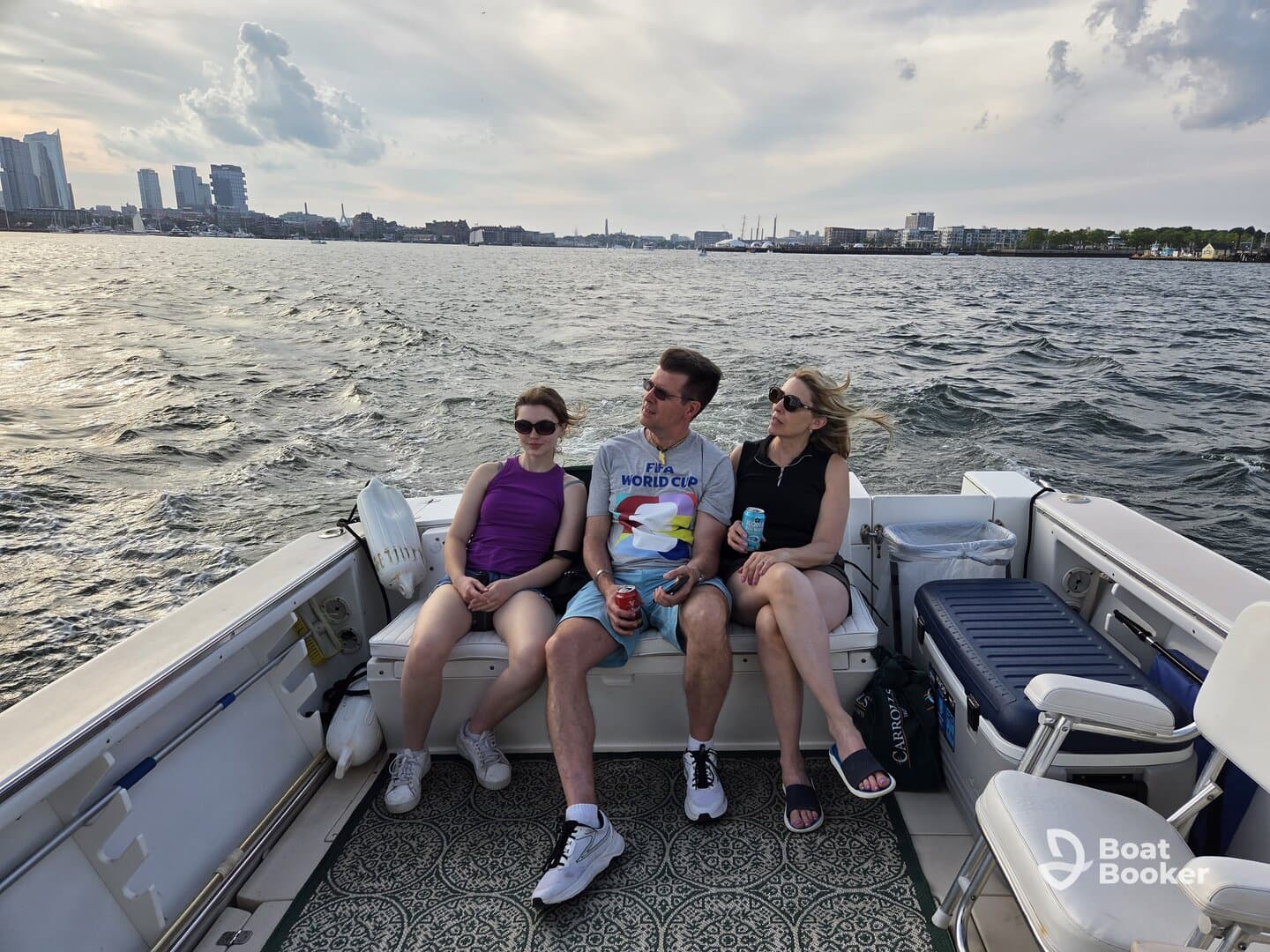 A group of friends relaxes on a boat, enjoying drinks and the scenic city skyline in the background — perfect for a leisurely day on the water.