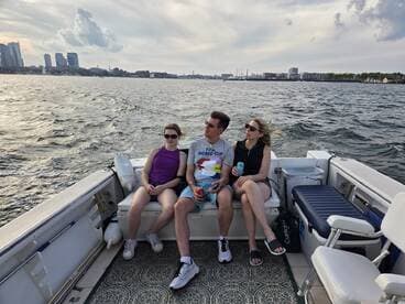 A group of friends relaxes on a boat, enjoying drinks and the scenic city skyline in the background — perfect for a leisurely day on the water.
