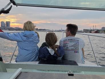 A family enjoys a scenic sunset view from their boat, capturing the beauty of the city skyline as they cruise along the water.