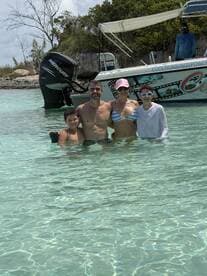 A joyful family enjoys a day in the shallow waters, creating unforgettable memories with their boat in the background — perfect for summer adventures.