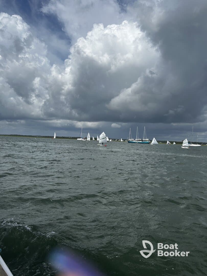 A scenic view of multiple sailboats participating in a regatta under a dramatic sky, showcasing the excitement of sailing on open waters.