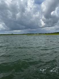 A scenic view of a waterway under a cloudy sky, with no identifiable subjects or activities.