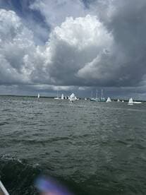 A scenic view of multiple sailboats participating in a regatta under a dramatic sky, showcasing the excitement of sailing on open waters.