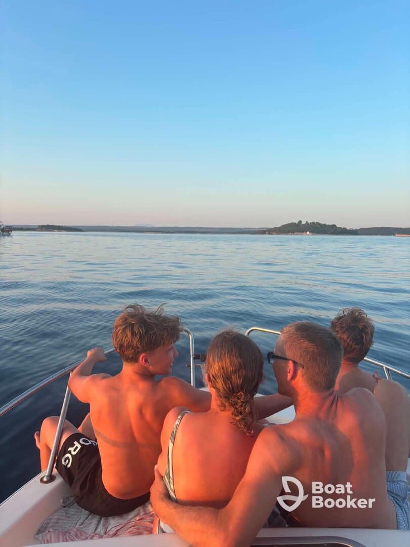A family enjoys a serene sunset view from their boat, creating lasting memories on the water. Perfect for family outings and relaxation.