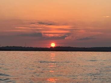 A stunning sunset over calm waters, creating a picturesque backdrop for evening boat outings.