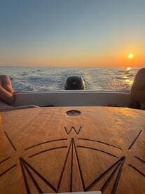 A serene sunset view from a boat, showcasing the calm ocean and relaxed passengers enjoying the tranquil atmosphere.