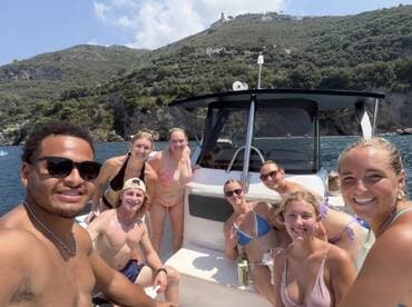 A lively group of friends enjoys a fun day on the boat, capturing memories against a stunning coastal backdrop — perfect for summer celebrations and adventures on the water.