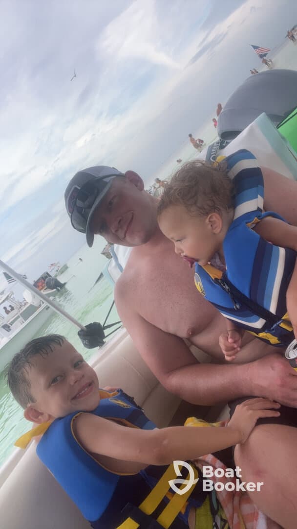 A father enjoys a fun day on the water with his two young children, all wearing life jackets, capturing a joyful family moment aboard a boat.