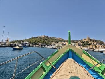 A vibrant view from the front of a boat, showcasing the picturesque harbor and hillside scenery — perfect for exploring coastal destinations.