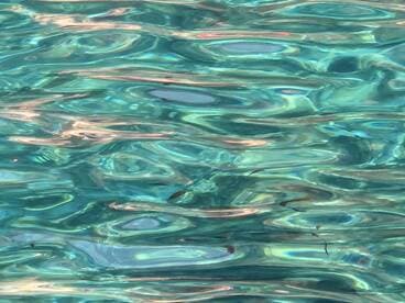 An abstract view of shimmering water, showcasing the beautiful reflections and colors, but lacking clear subjects or context.