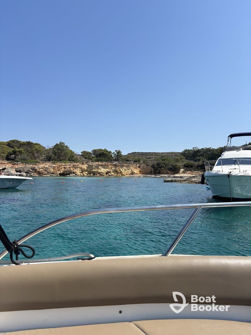 A scenic view from the bow of a boat, showcasing the tranquil waters and nearby vessels in a picturesque harbor setting.