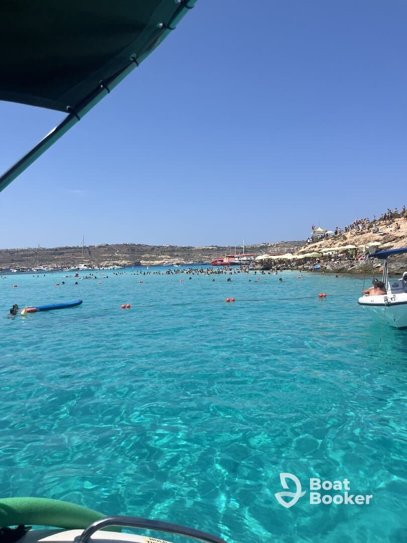 A vibrant scene at a popular beach with clear turquoise waters, showcasing people enjoying swimming and sunbathing — a perfect destination for summer fun.