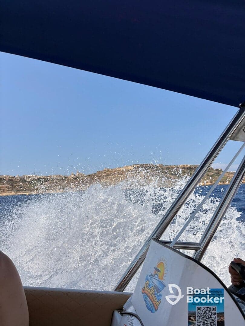 A thrilling moment on the water as the boat speeds through waves, creating splashes against a scenic backdrop — perfect for adventure seekers enjoying their day out at sea.