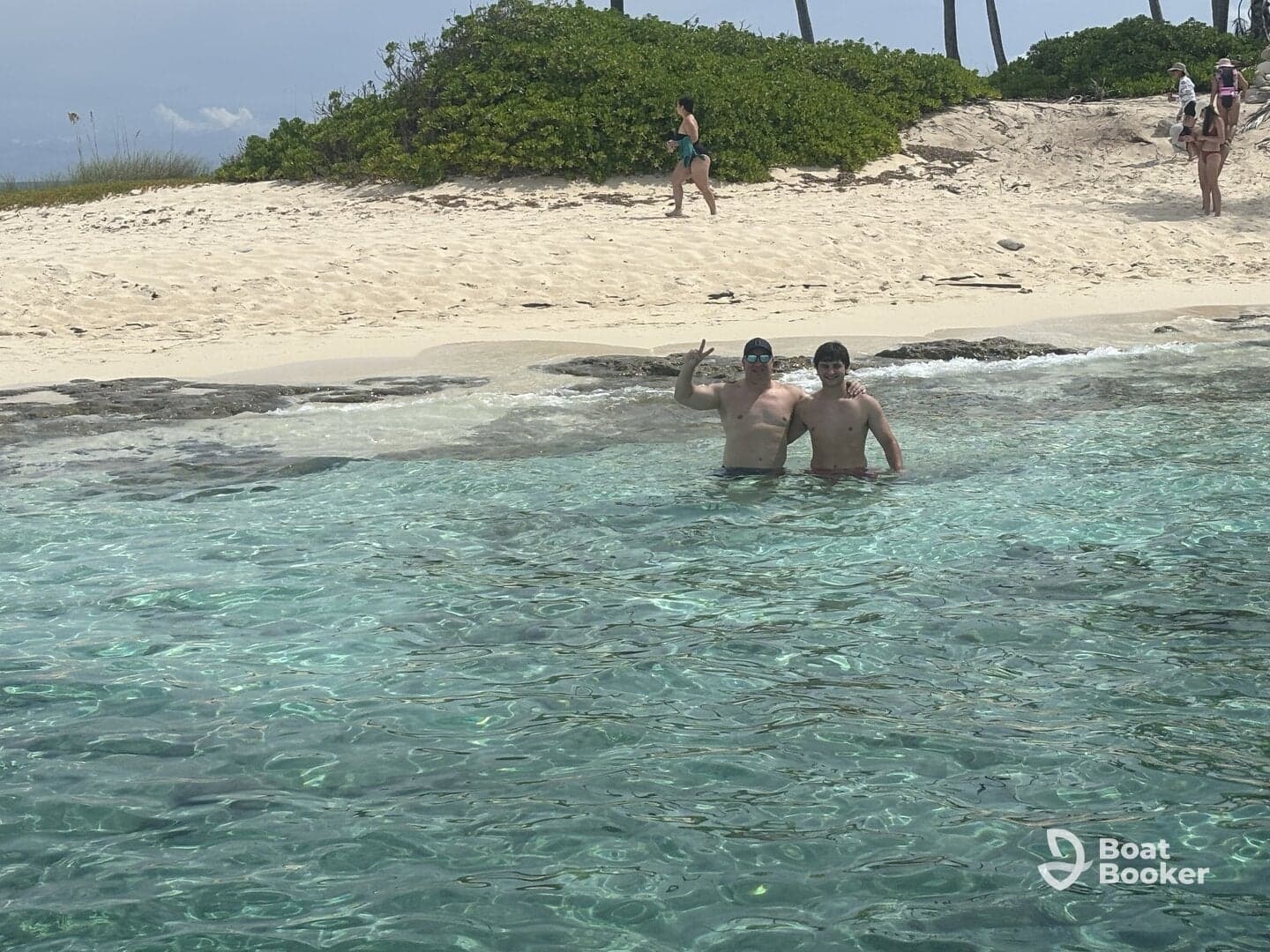 Two friends enjoy a refreshing swim in crystal-clear waters near a sandy beach, capturing the essence of a fun day in the sun.