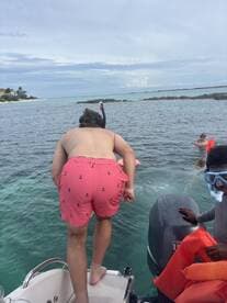 A group of friends prepares to snorkel in crystal-clear waters, showcasing the excitement of water activities and adventure on a boat trip.