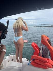 A young woman prepares to snorkel off the side of a boat, ready to explore the vibrant underwater world — a perfect moment for adventure seekers.