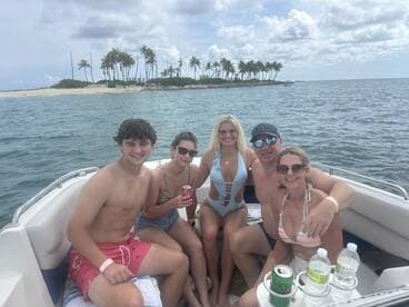 A cheerful group enjoys a day on the water, capturing the essence of fun and relaxation aboard their boat, surrounded by a beautiful tropical backdrop.