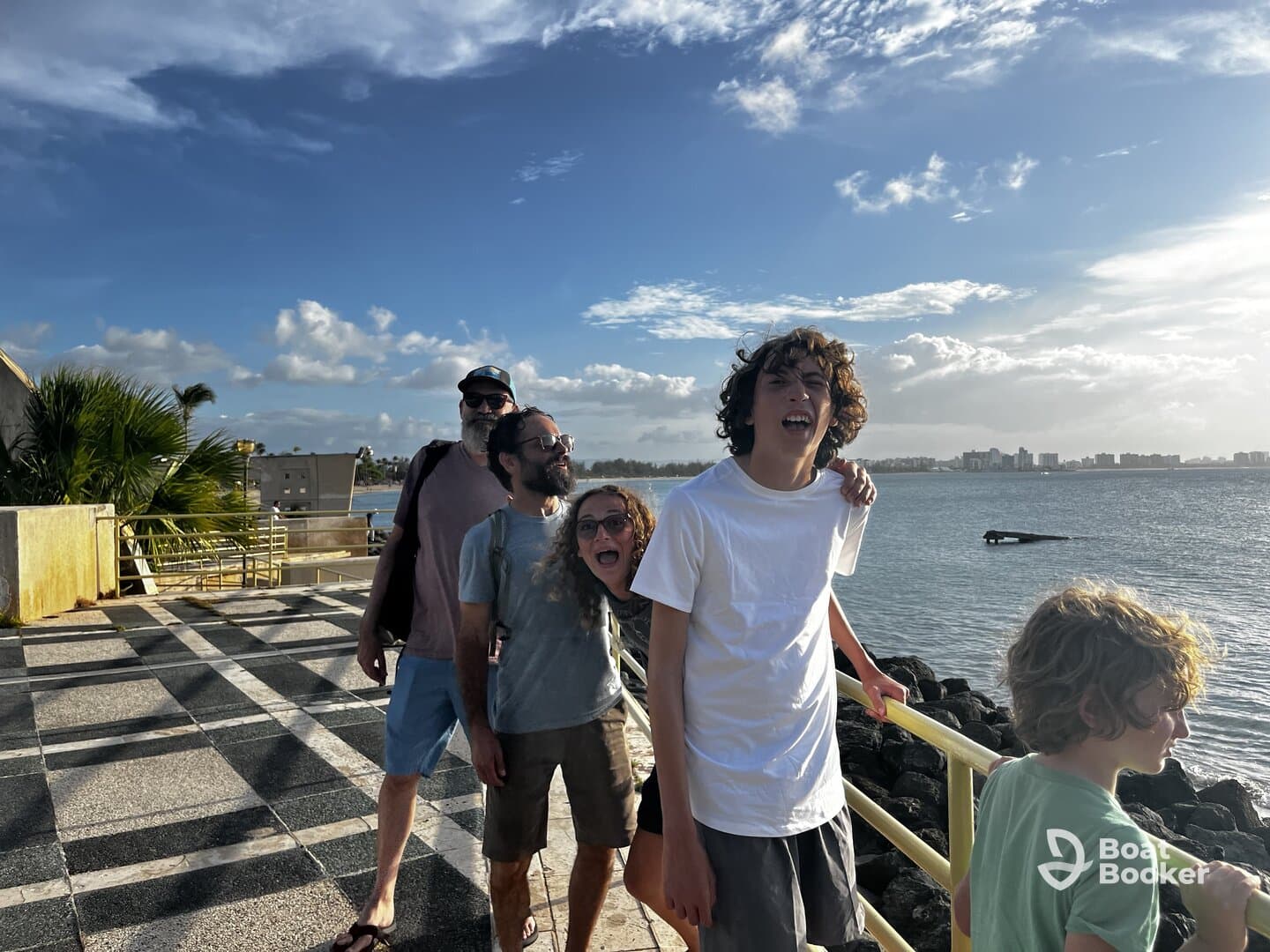A joyful family poses by the ocean, capturing a fun moment together with a beautiful waterfront backdrop.