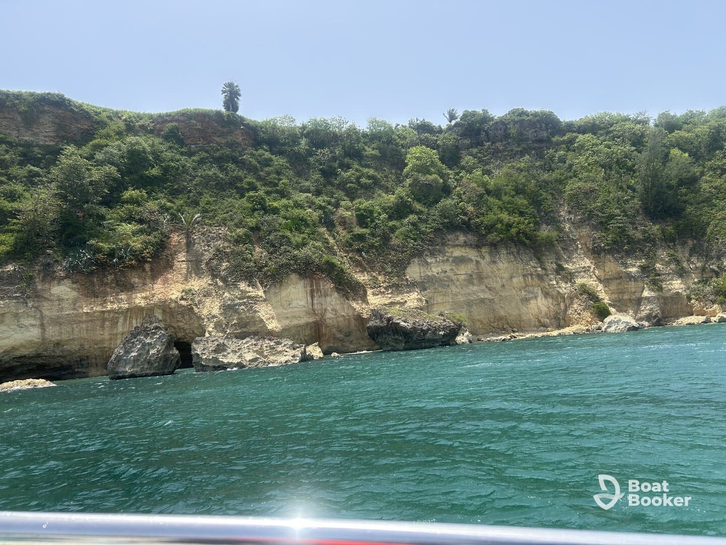 A stunning view of a rugged coastline with lush greenery and clear turquoise waters, perfect for exploring by boat.