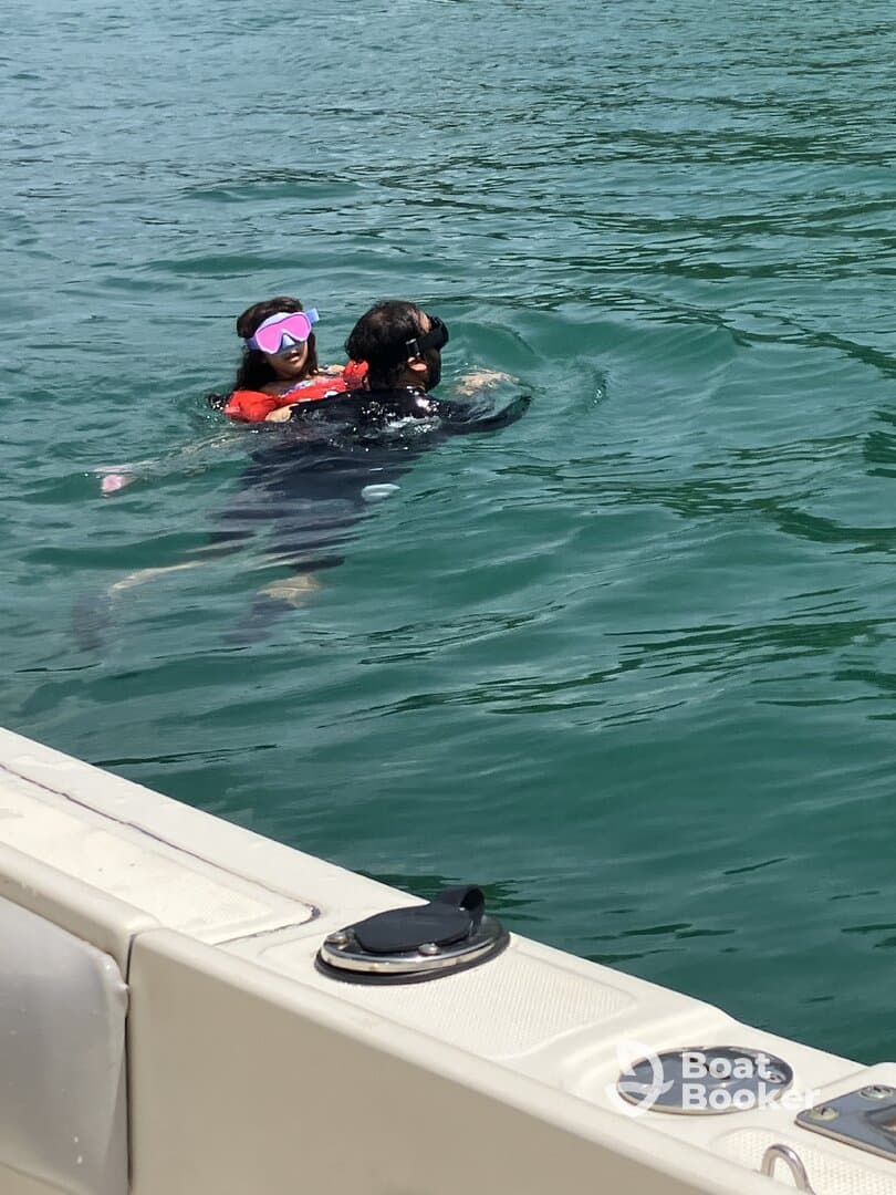 A child enjoys a fun swimming experience with an adult in clear waters, showcasing a delightful family moment on the water.
