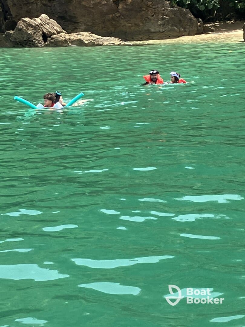 A family enjoys a fun day swimming in crystal-clear waters, with kids using pool noodles and snorkeling gear — a perfect beach adventure.