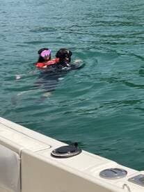 A child enjoys a fun swimming experience with an adult in clear waters, showcasing a delightful family moment on the water.