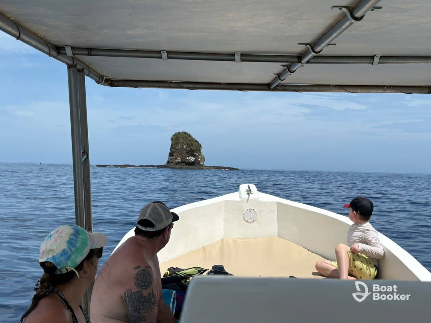 A family enjoys a scenic boat ride, gazing at a rocky island in the distance — a perfect moment for adventure seekers exploring the ocean.