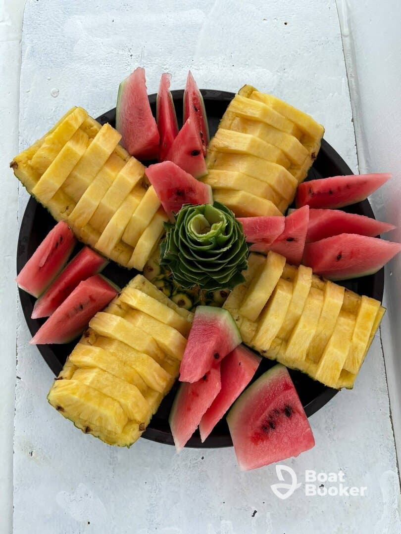 A beautifully arranged platter of fresh pineapple and watermelon, perfect for enjoying on a boat trip or during a sunny day at sea.