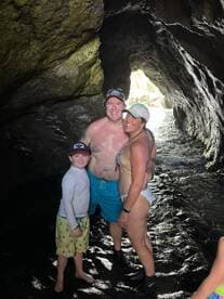 A joyful family poses together inside a cave, capturing a memorable moment during their aquatic adventure — perfect for family outings and exploration.