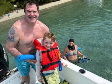 A joyful family enjoys a snorkeling adventure in clear waters, with a child in a life jacket and adults ready for underwater exploration.