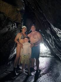 A joyful family poses inside a cave, enjoying their beach adventure — a perfect moment capturing fun and exploration.