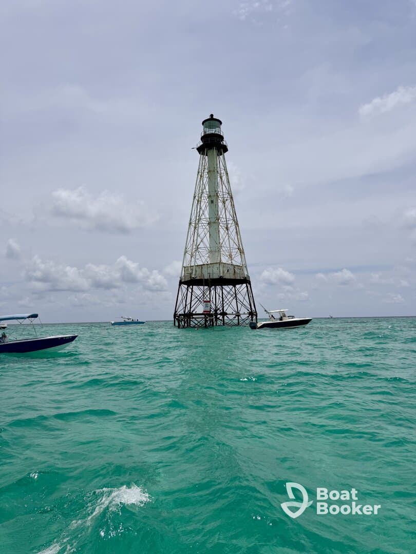A stunning view of a lighthouse standing tall amidst turquoise waters, surrounded by boats — a picturesque landmark perfect for sightseeing and exploration.