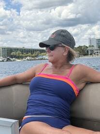 A woman enjoys a relaxing moment on a boat, soaking in the sun and the beautiful water views — perfect for a day out on the water.