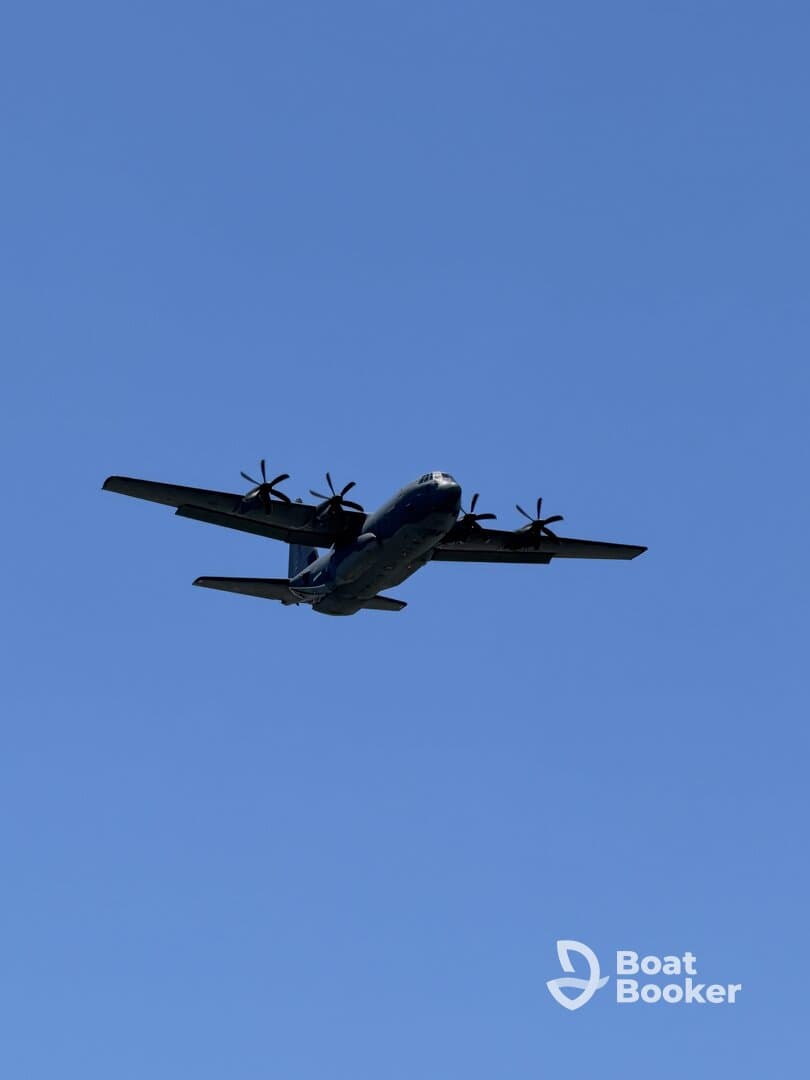 An aircraft is captured flying against a clear blue sky, but the image does not relate to boating or water activities.