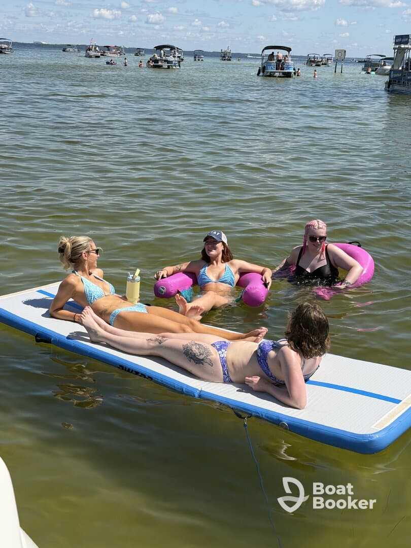 A fun group of friends relaxes on a floating mat in the water, enjoying a sunny day filled with laughter and good vibes — perfect for summer outings.