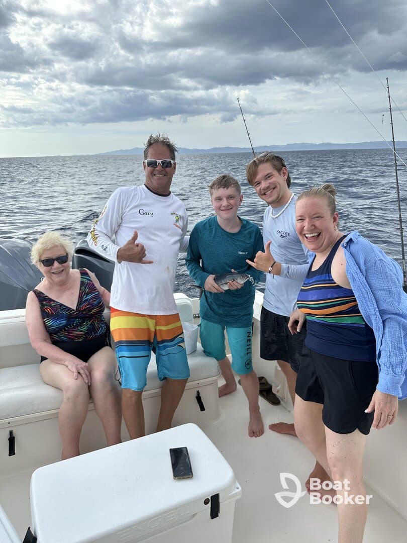 A joyful group poses for a photo on a fishing trip, showcasing their catch and enjoying a memorable day on the ocean.