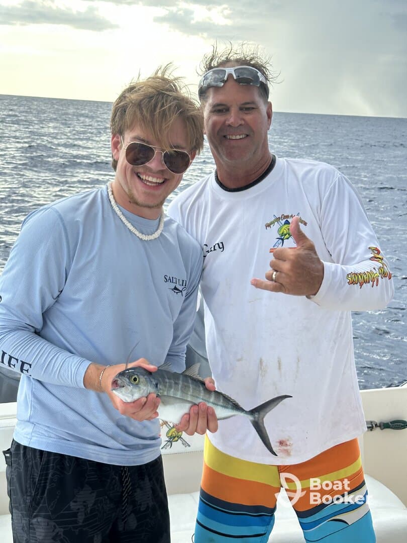 Two anglers proudly display their catch while enjoying a fishing trip at sea, capturing the thrill of the experience.