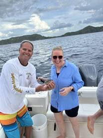 A joyful moment as two friends celebrate their fishing catch aboard a boat, showcasing the excitement of a day on the water.