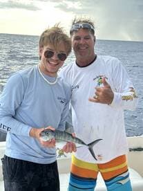 Two anglers proudly display their catch while enjoying a fishing trip at sea, capturing the thrill of the experience.