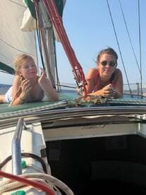 Two young girls enjoy a sunny day sailing, relaxing on the deck of a boat — a perfect moment of fun and adventure on the water.