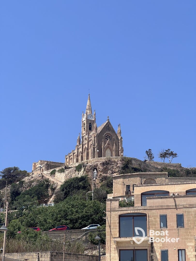 A scenic view of a church perched on a hill, surrounded by greenery and buildings, showcasing the architectural beauty of the area.