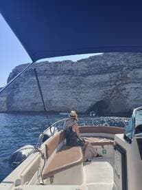 A woman relaxes on the deck of a boat, enjoying the stunning cliffside scenery — a perfect moment for unwinding on the water.