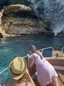 A child and an adult lean over the side of a boat, captivated by the stunning rock formations and clear waters, showcasing a memorable family adventure on the water.