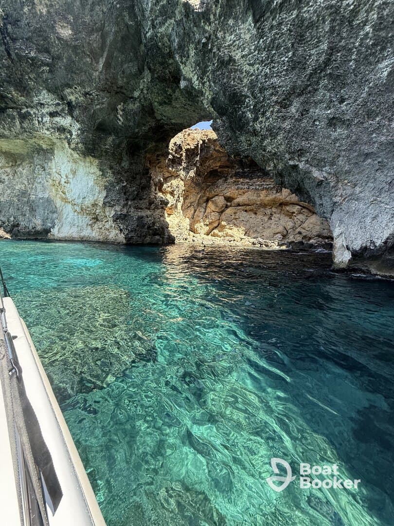 A stunning view of a natural rock arch over crystal-clear turquoise waters, showcasing the breathtaking coastline and inviting exploration.