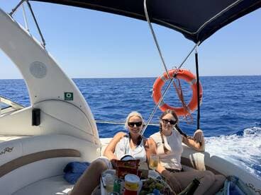 Two friends enjoy drinks and snacks on a boat, capturing the essence of a fun day at sea with beautiful ocean views.